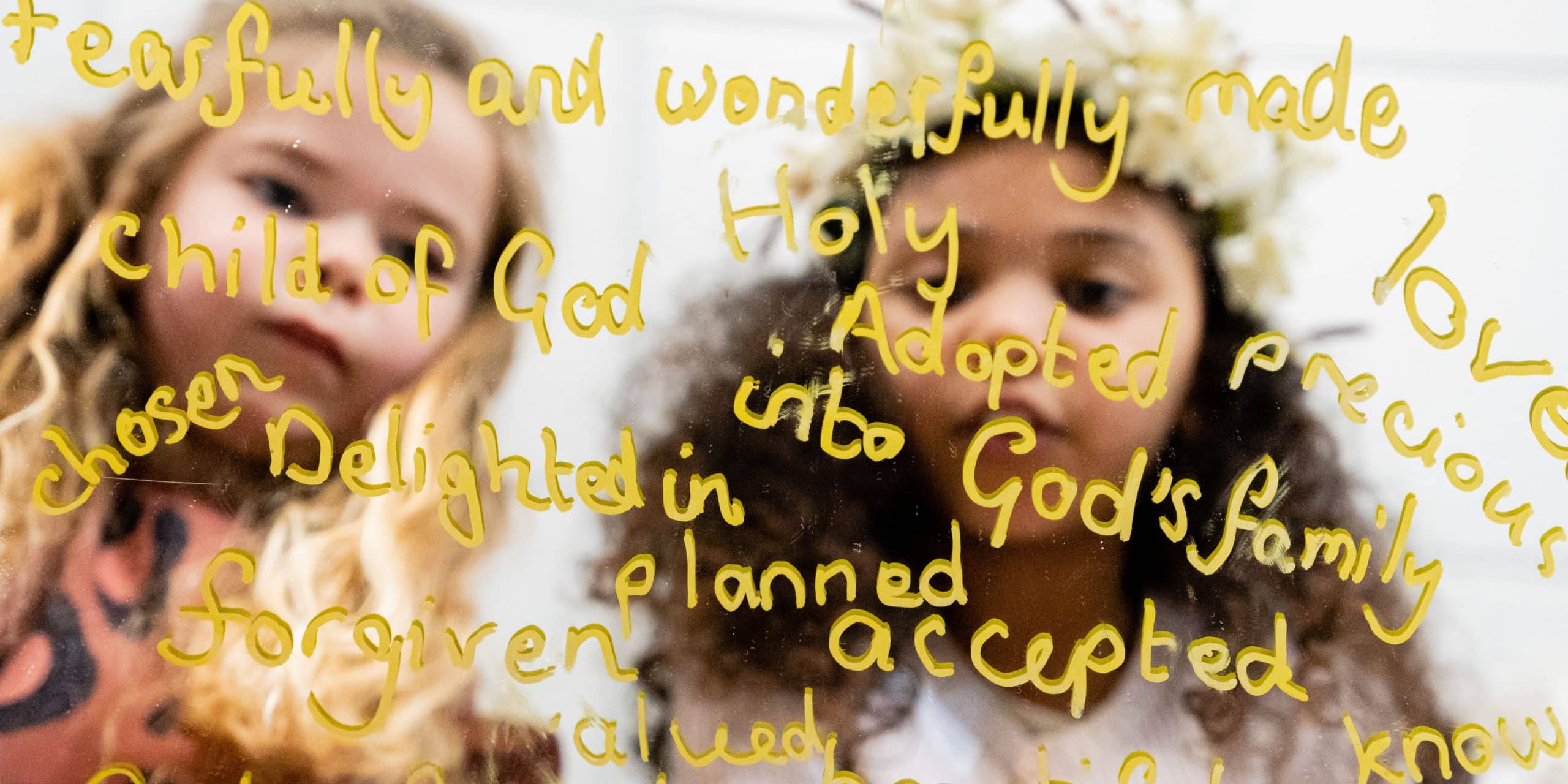 children looking into a mirror with words of identity written on