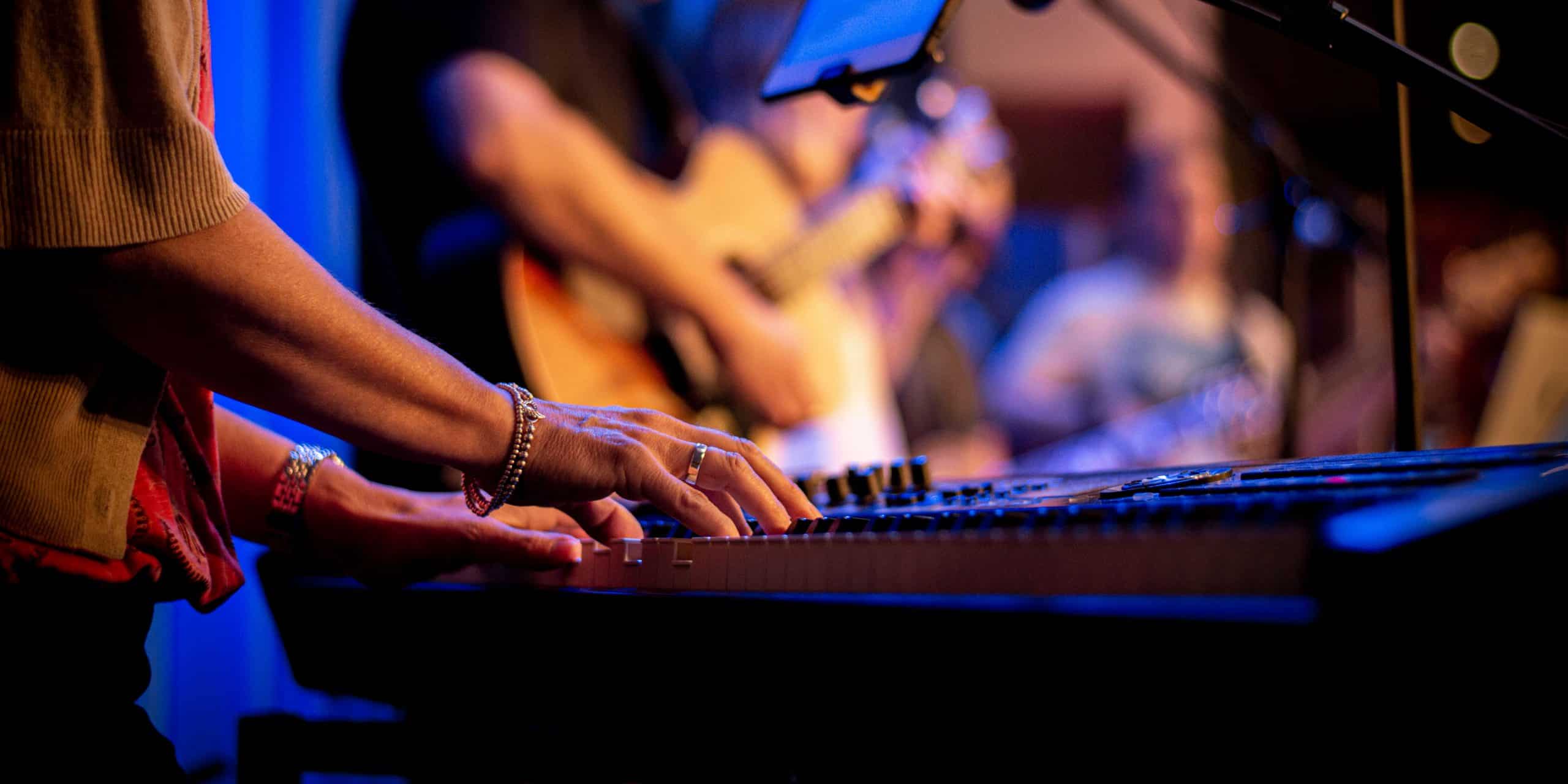 somebody playing piano with guitarist in background