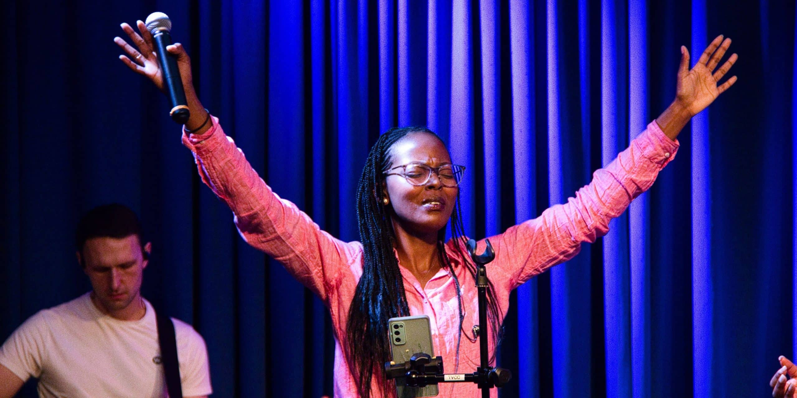 lady on stage with arms raised in worship