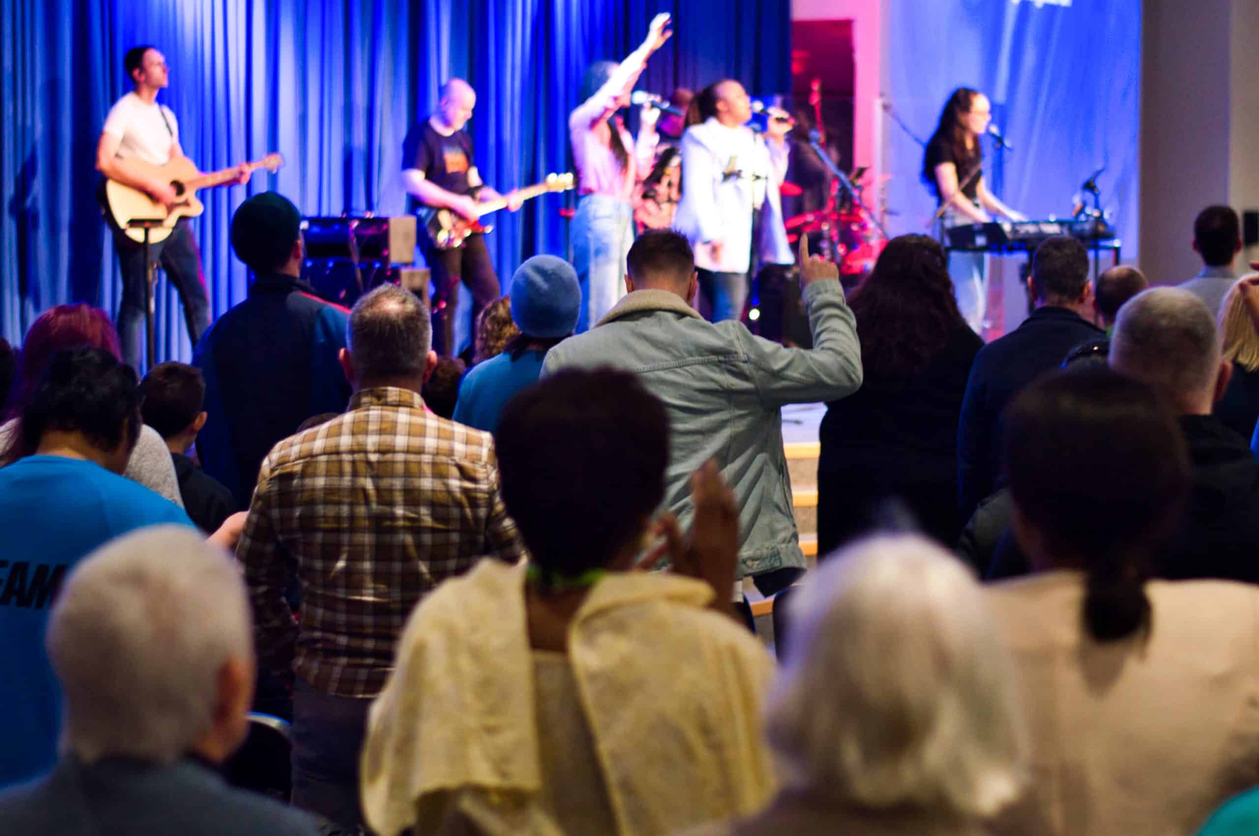 TVCC congregation worshiping on a Sunday Morning, in the background the Worship Team are leading worship on stage